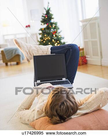 Stock Photography - Young woman lying on floor with laptop. Fotosearch