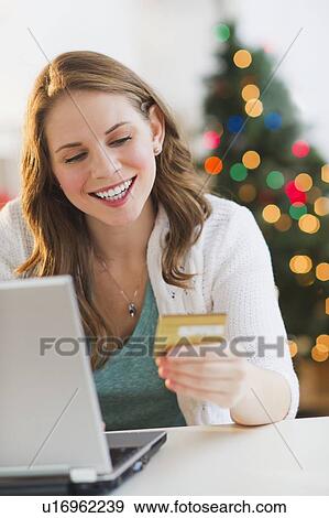 Young woman on-line shopping from home with Christmas tree on background View Large Photo Image Stock Photo - Young woman on-line shopping from home with Christmas tree on background. Fotosearch