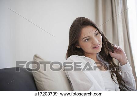 Young woman sitting on couch View Large Photo Image Stock Photo - Young woman sitting on couch. Fotosearch