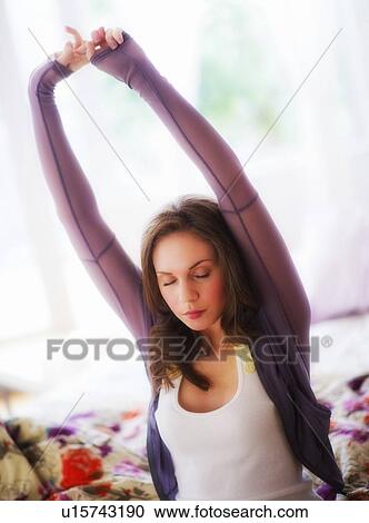 Young woman stretching on bed View Large Photo Image Stock Image - Young woman stretching on bed. Fotosearch