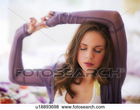 Stock Photo - Young woman stretching on bed. Fotosearch