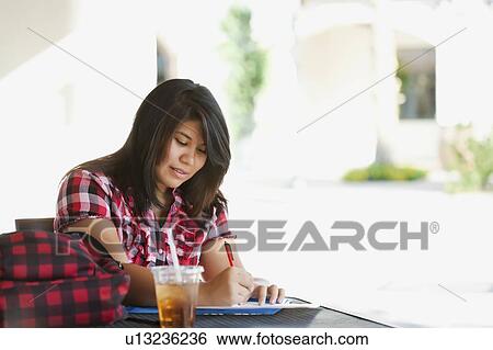 Stock Photograph - Young woman studying in outdoor cafe. Fotosearch