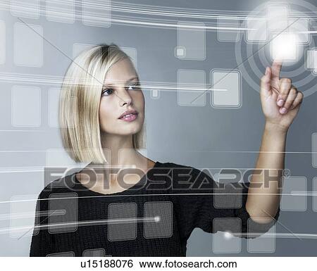 Stock Photograph - Young woman using futuristic touchscreen, studio shot. Fotosearch