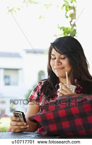 Young woman using phone in outdoor cafe View Large Photo Image Stock Image - Young woman using phone in outdoor cafe. Fotosearch