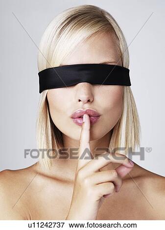 Young woman wearing blindfold with finger on lips, studio shot View Large Photo Image Stock Photo - Young woman wearing blindfold with finger on lips, studio shot. Fotosearch