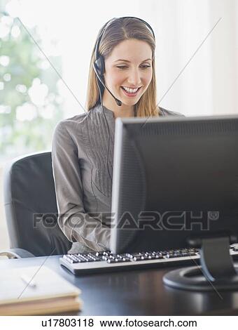 Young woman with headphones on computer View Large Photo Image Stock Photo - Young woman with headphones on computer. Fotosearch