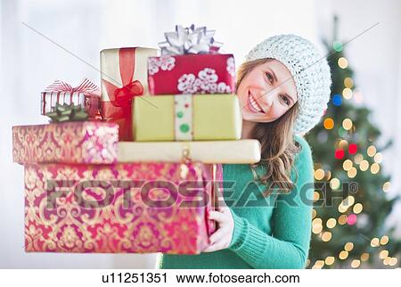 Young woman with stack of colorful Christmas gifts View Large Photo Image Stock Image - Young woman with stack of colorful Christmas gifts. Fotosearch