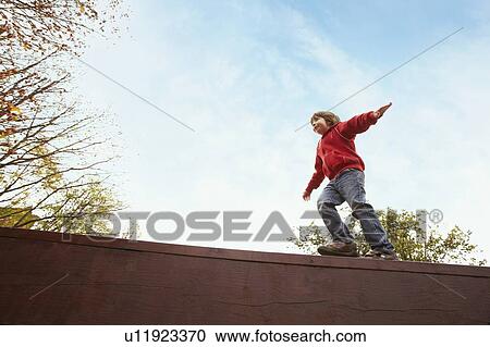 Boy balancing on wooden wall View Large Photo Image Stock Image - Boy balancing on wooden wall. Fotosearch