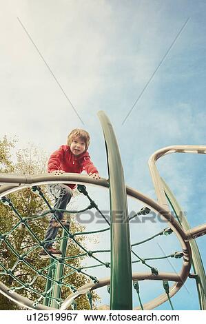 Stock Photo - Boy climbing on jungle gym at park. Fotosearch