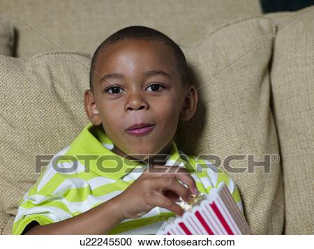 Boy eating popcorn on couch View Large Photo Image Stock Image - Boy eating popcorn on couch. Fotosearch