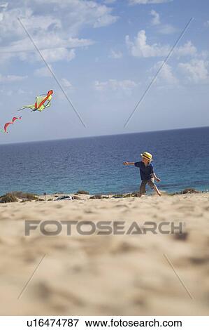 Stock Photo - Boy flying kite on beach. Fotosearch