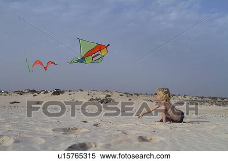 Stock Photography - Boy flying kite on beach. Fotosearch