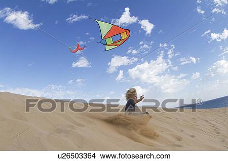 Boy flying kite on sand dune View Large Photo Image Picture - Boy flying kite on sand dune. Fotosearch