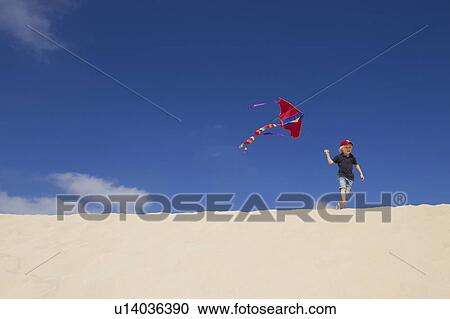 Boy flying kite on sand dune View Large Photo Image Stock Image - Boy flying kite on sand dune. Fotosearch