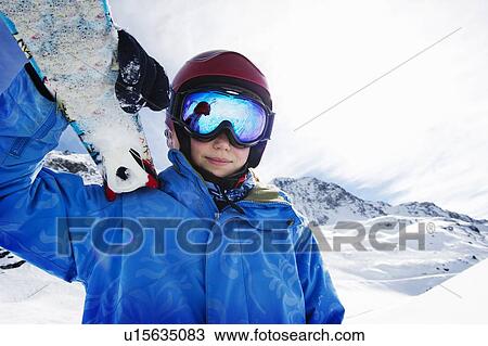 Stock Image - Boy holding skis on snowy mountain. Fotosearch
