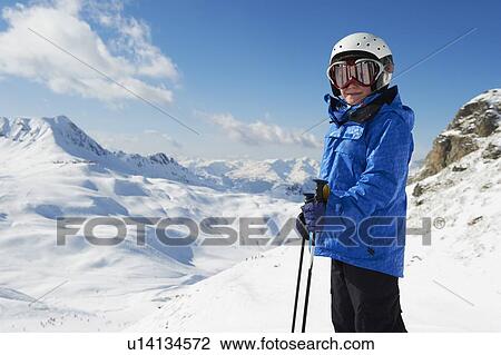 Stock Image - Boy in skis on snowy mountaintop. Fotosearch