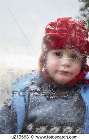 Stock Image - Boy looking in frosty window. Fotosearch