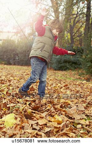 Stock Image - Boy playing in autumn leaves. Fotosearch