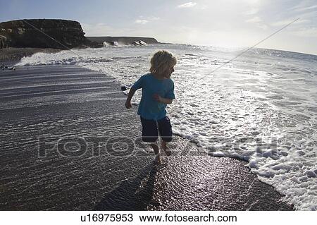 Boy playing in waves on beach View Large Photo Image Stock Image - Boy playing in waves on beach. Fotosearch