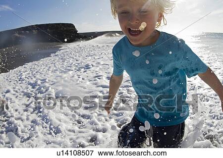 Boy playing in waves on beach View Large Photo Image Stock Photo - Boy playing in waves on beach. Fotosearch