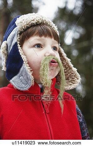 Stock Image - Boy playing with moss outdoors. Fotosearch