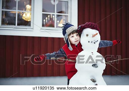 Boy playing with snowman outdoors View Large Photo Image Stock Photography - Boy playing with snowman outdoors. Fotosearch