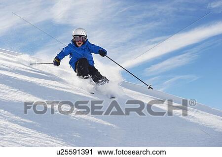 Stock Image - Boy skiing on snowy mountainside. Fotosearch