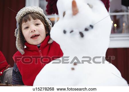 Boy standing behind snowman View Large Photo Image Stock Photo - Boy standing behind snowman. Fotosearch