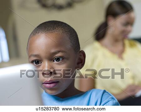 Stock Image - Boy using laptop in living room. Fotosearch