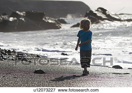 Boy walking in waves on beach View Large Photo Image Stock Photo - Boy walking in waves on beach. Fotosearch