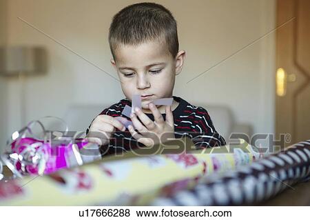 Stock Photo - Boy wrapping presents at desk. Fotosearch