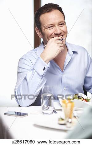 Stock Image - Businessman eating salad in cafe. Fotosearch