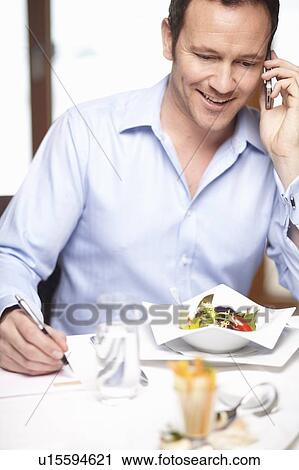 Stock Image - Businessman on cell phone in cafe. Fotosearch