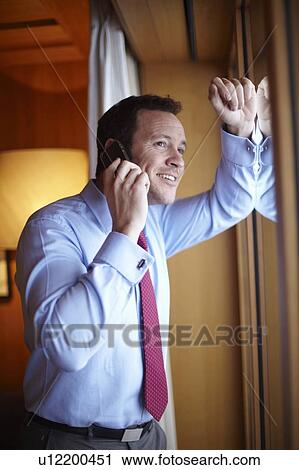 Businessman on cell phone in hotel room View Large Photo Image Stock Image - Businessman on cell phone in hotel room. Fotosearch