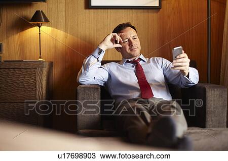 Businessman on cell phone in hotel room View Large Photo Image Stock Image - Businessman on cell phone in hotel room. Fotosearch
