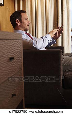 Stock Image - Businessman on cell phone in hotel room. Fotosearch