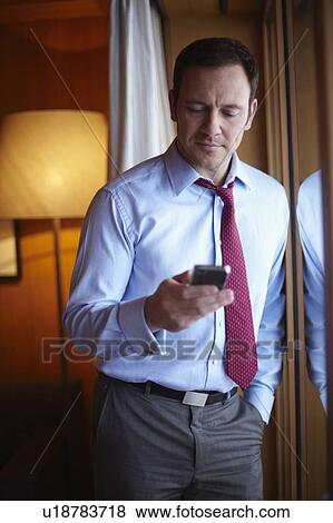 Businessman on cell phone in hotel room View Large Photo Image Stock Photo - Businessman on cell phone in hotel room. Fotosearch