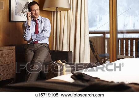 Stock Photography - Businessman on cell phone in hotel room. Fotosearch