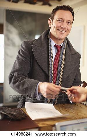 Businessman paying at hotel front desk View Large Photo Image Stock Image - Businessman paying at hotel front desk. Fotosearch