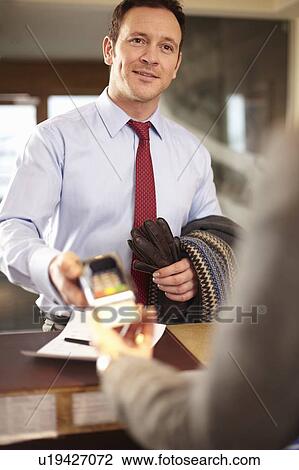 Businessman paying at hotel front desk View Large Photo Image Stock Image - Businessman paying at hotel front desk. Fotosearch