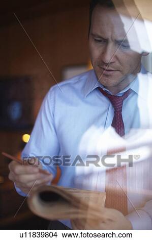 Businessman reading newspaper at window View Large Photo Image Picture - Businessman reading newspaper at window. Fotosearch