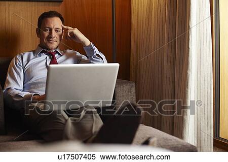Stock Photography - Businessman using laptop in hotel room. Fotosearch