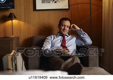 Stock Photo - Businessman using tablet in hotel room. Fotosearch