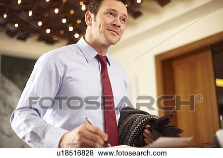 Businessman writing at hotel front desk View Large Photo Image Stock Photo - Businessman writing at hotel front desk. Fotosearch