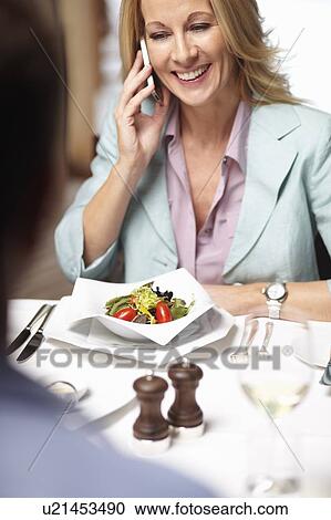 Stock Image - Businesswoman on cell phone in cafe. Fotosearch