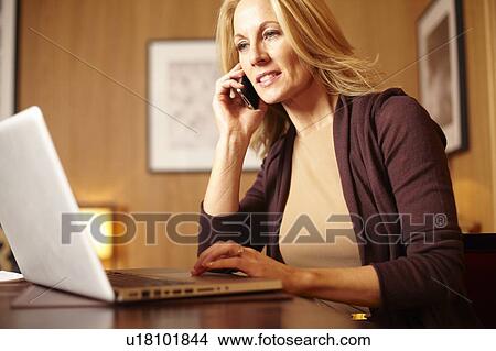 Picture - Businesswoman using laptop in hotel room. Fotosearch