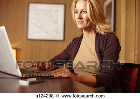 Stock Image - Businesswoman using laptop in hotel room. Fotosearch