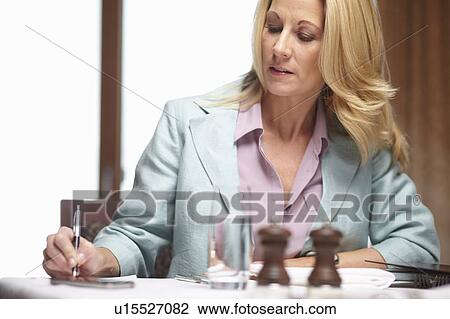 Stock Image - Businesswoman writing in cafe. Fotosearch
