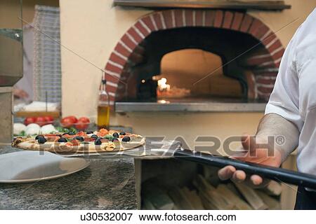 Stock Photo - Chef holding pizza on spatula. Fotosearch