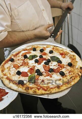 Stock Photograph - Chef holding pizza on spatula. Fotosearch
